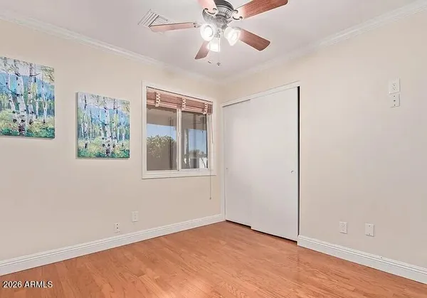 a view of an empty room with a window and wooden floor