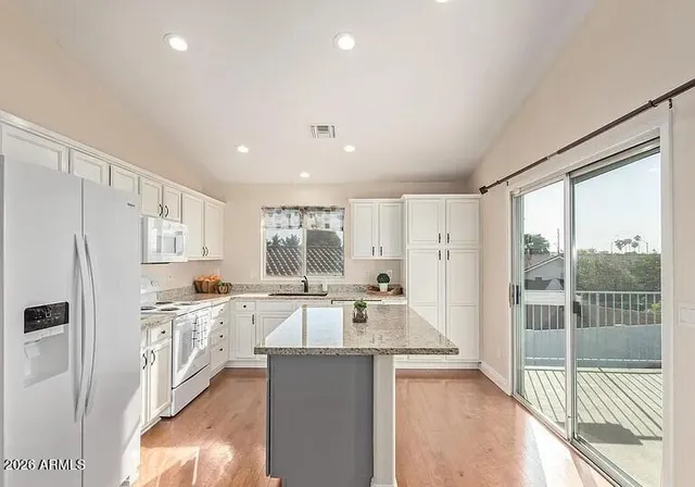 a kitchen with stainless steel appliances granite countertop a refrigerator a sink dishwasher a stove and white countertops with wooden floor