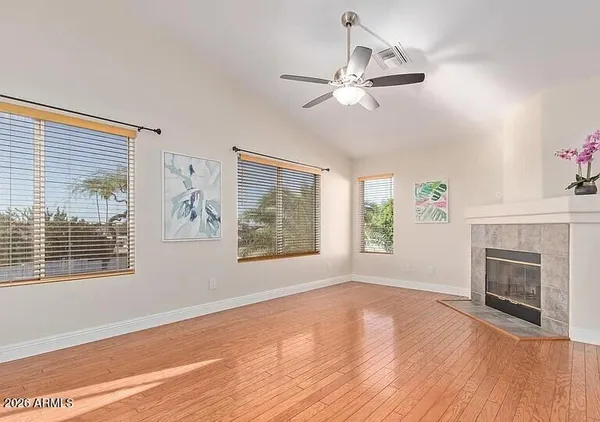 a view of an empty room with wooden floor fireplace and a window