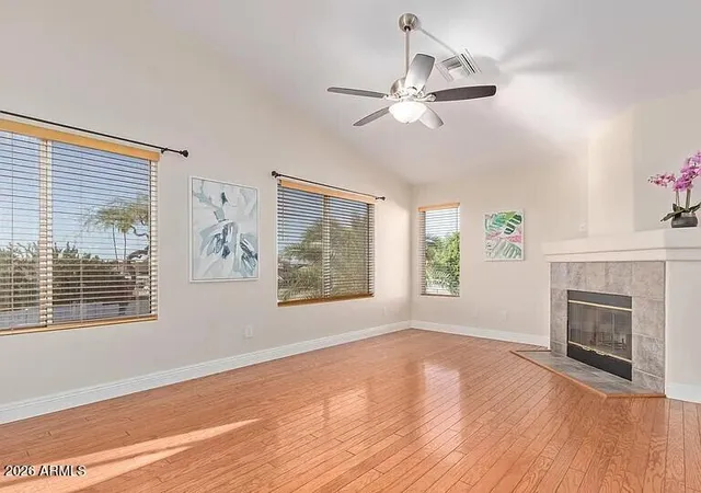 a view of an empty room with wooden floor fireplace and a window