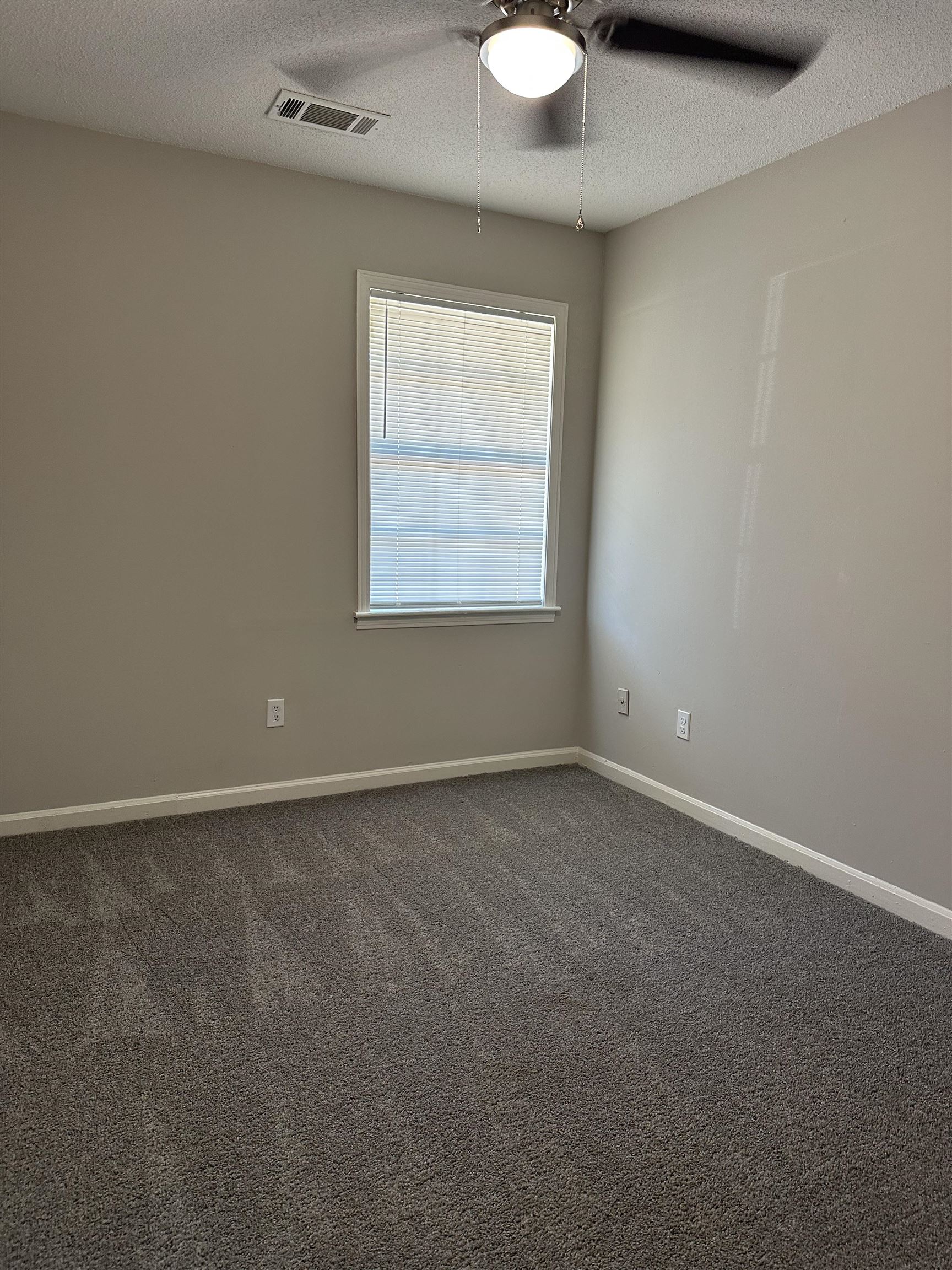 899 West Raines Road Memphis, TN 38109 - Photo 10 of 14 Neutral wall color, window with blinds, ceiling fan with integrated lighting, and patterned carpeting