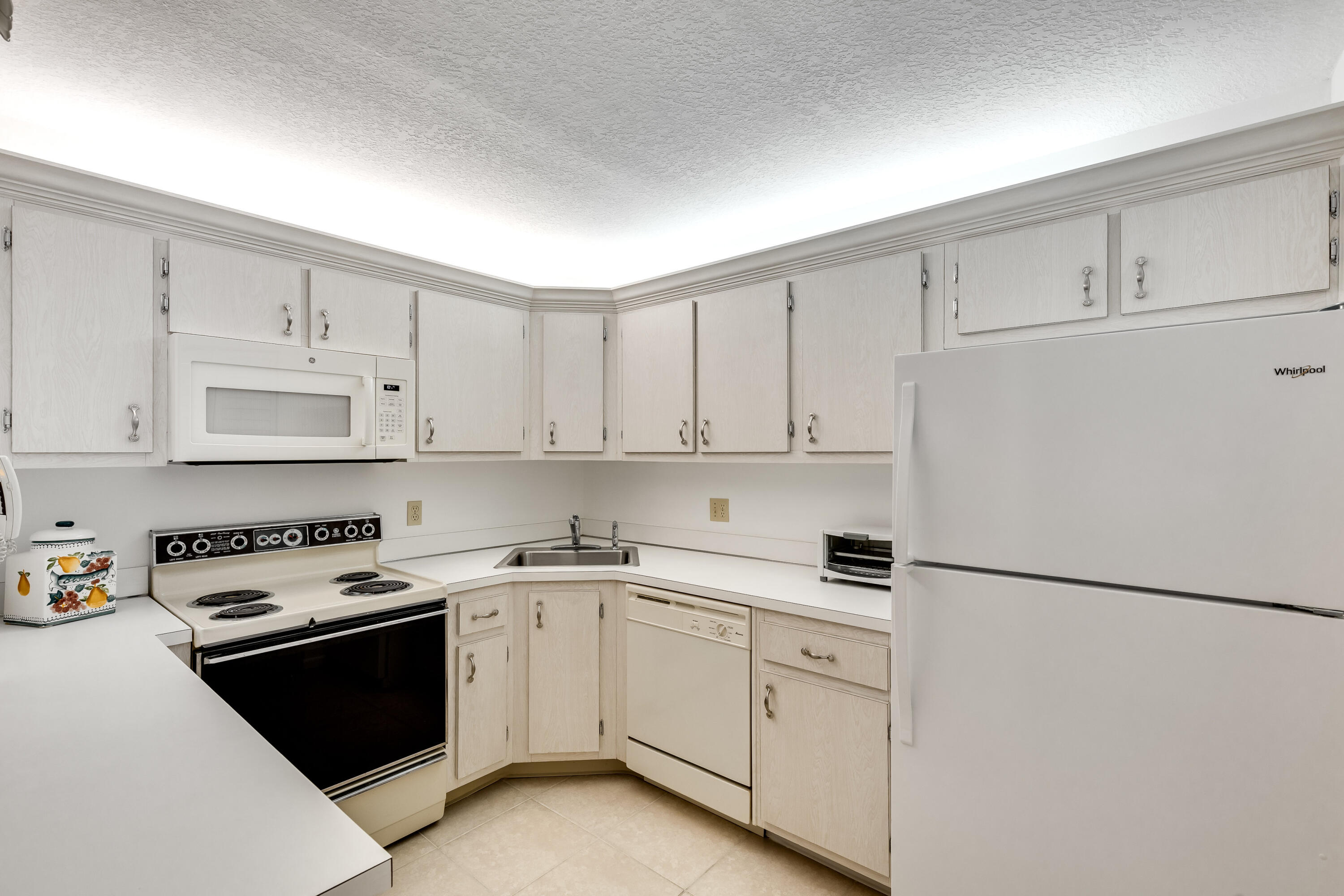 122 Lake Pine Circle, Unit B1 Greenacres, FL 33463 - Photo 14 of 36 a kitchen with white cabinets and white appliances