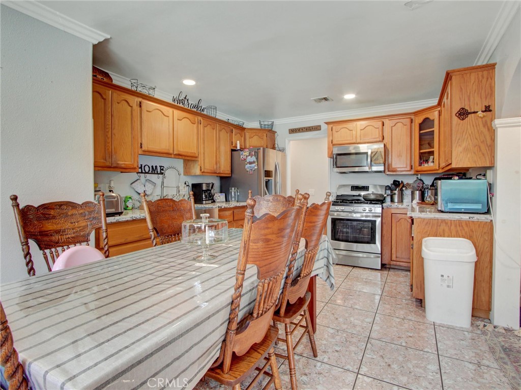10922 Vickers Drive Garden Grove, CA 92840 - Photo 9 of 25 a kitchen with stainless steel appliances kitchen island granite countertop a stove a sink a dining table and chairs