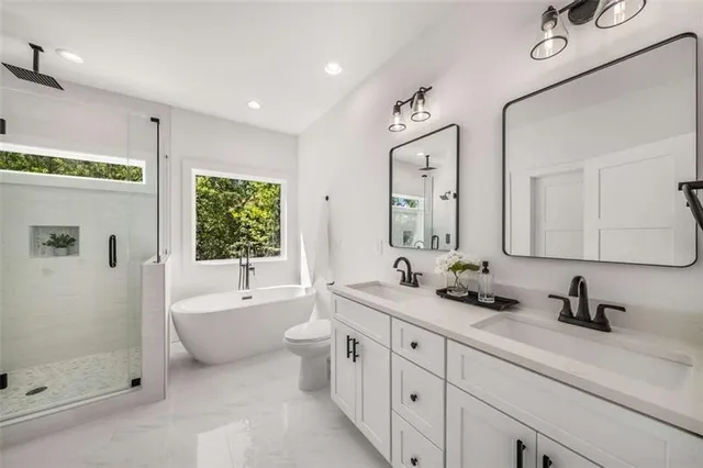 a spacious bathroom with a double vanity sink a large mirror and a bathtub