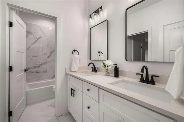 a bathroom with a double vanity sink a mirror and a bathtub