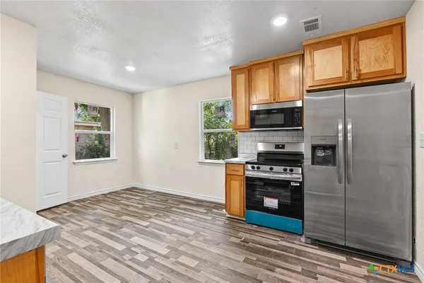 a kitchen with stainless steel appliances granite countertop a refrigerator a stove a sink and a microwave