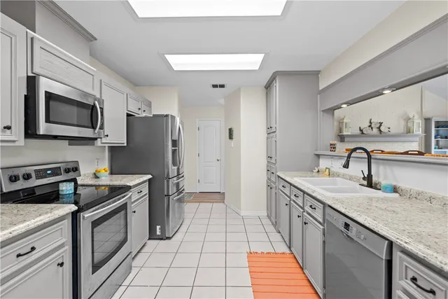 a kitchen with stainless steel appliances granite countertop a sink stove microwave and refrigerator