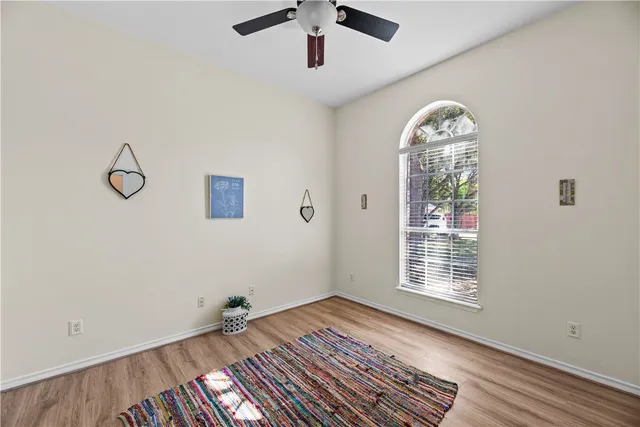 a view of an empty room with a window and wooden floor