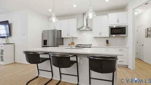 a kitchen with stainless steel appliances granite countertop a sink a stove a refrigerator and island with wooden floor