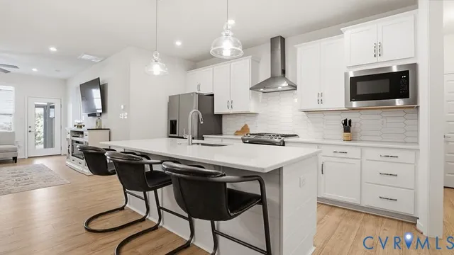 a kitchen with stainless steel appliances kitchen island granite countertop a table chairs and a wooden floor