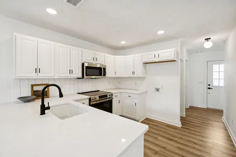 a kitchen with stainless steel appliances kitchen island sink refrigerator and cabinets