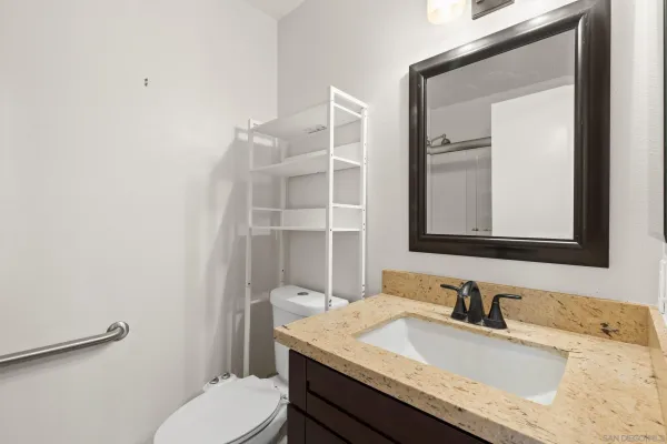 a bathroom with a granite countertop sink vanity mirror and toilet