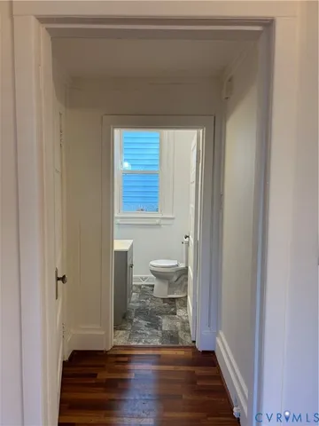 a view of a bathroom with toilet window and wooden floor
