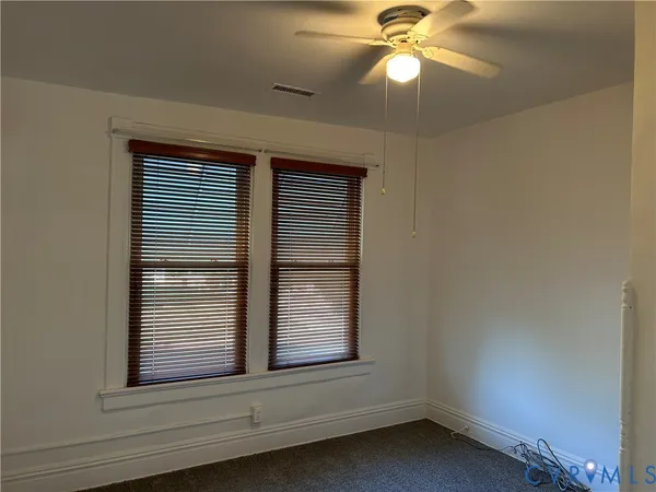 a view of wooden floor and a chandelier fan in a room