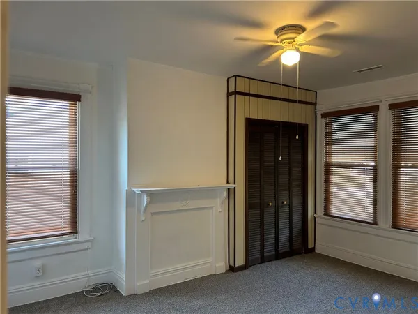a view of a livingroom with a chandelier fan and windows