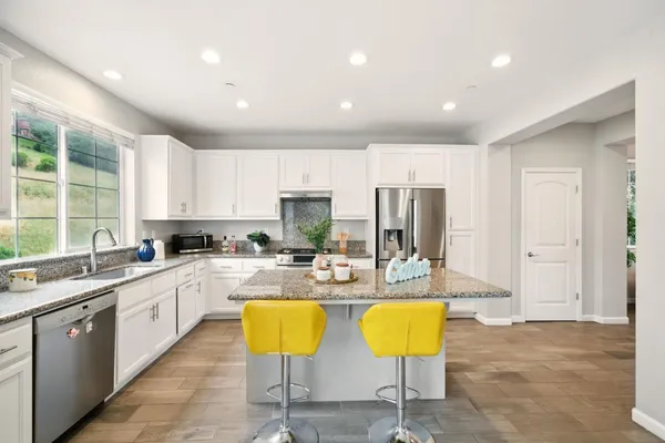 a kitchen with stainless steel appliances kitchen island granite countertop a sink and white cabinets
