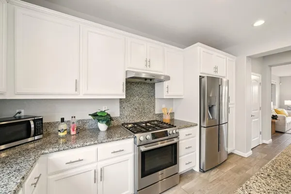 a kitchen with stainless steel appliances granite countertop a refrigerator sink and stove