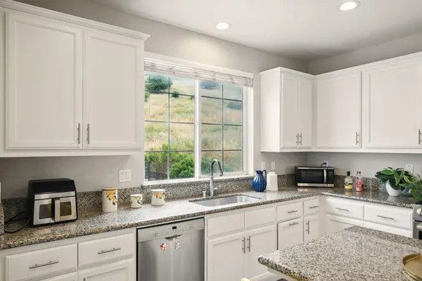 a kitchen with granite countertop white cabinets and window