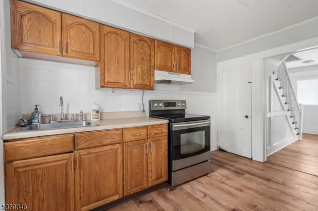 a kitchen with stainless steel appliances granite countertop a sink a stove a refrigerator and cabinets with wooden floor