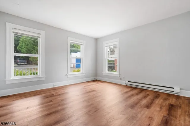 a view of an empty room with wooden floor and window