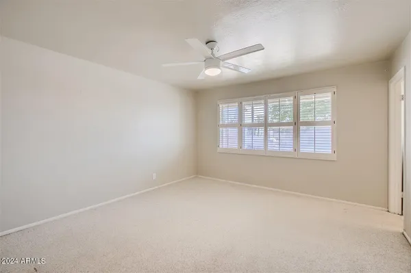 an empty room with a window and a ceiling fan