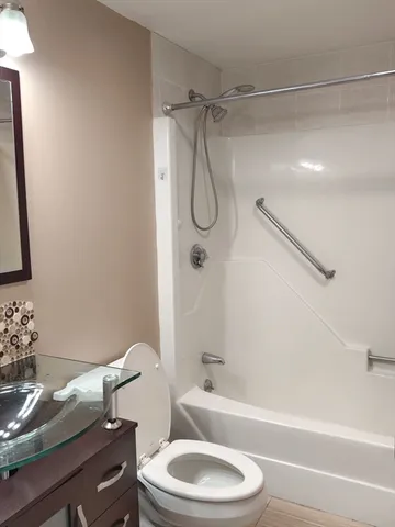 a bathroom with a granite countertop bathtub shower sink vanity and toilet