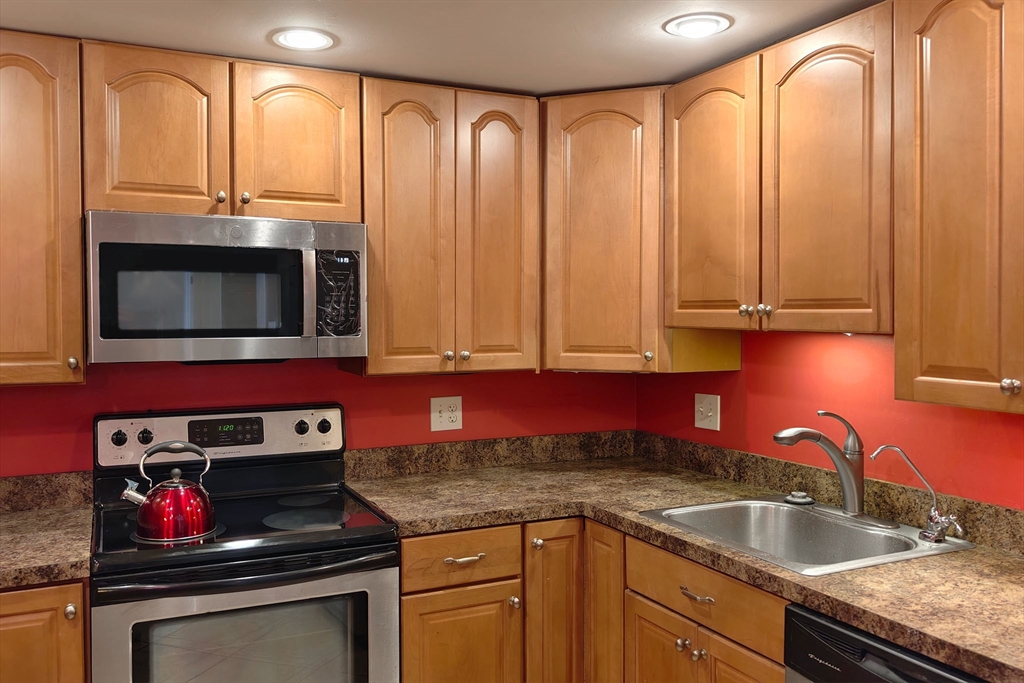 8 9th Street, Unit 406 Medford, MA 02155 - Photo 7 of 21 a kitchen with stainless steel appliances granite countertop a sink a stove and a microwave