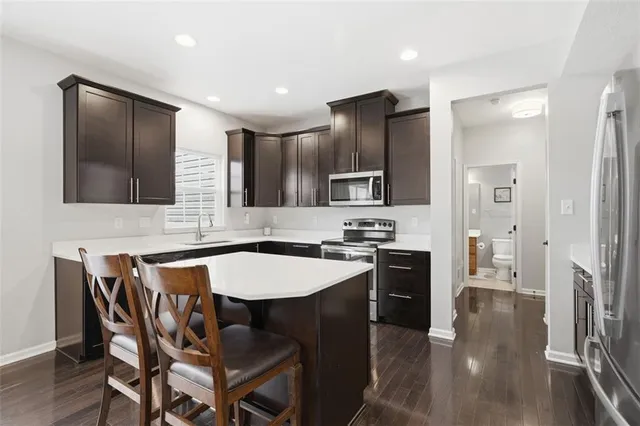 a kitchen with stainless steel appliances granite countertop a sink a stove a refrigerator with a dining table and chairs