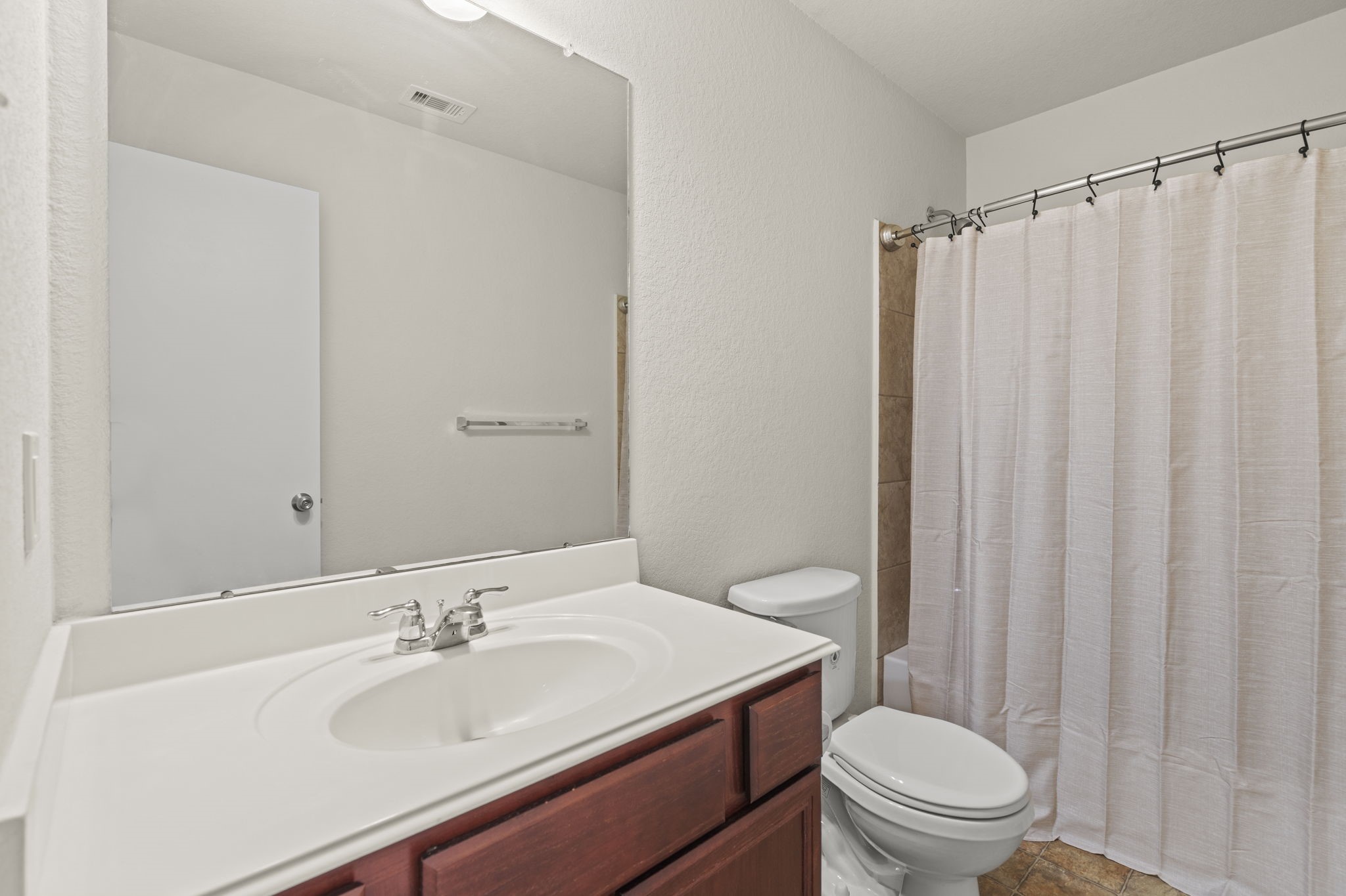 2110 Red Cedar Trail Rosenberg, TX 77471 - Photo 14 of 20 A functional full bathroom featuring a spacious single-sink vanity with under-cabinet storage and an expansive vanity mirror. The space includes a standard toilet and a tiled tub/shower enclosure.