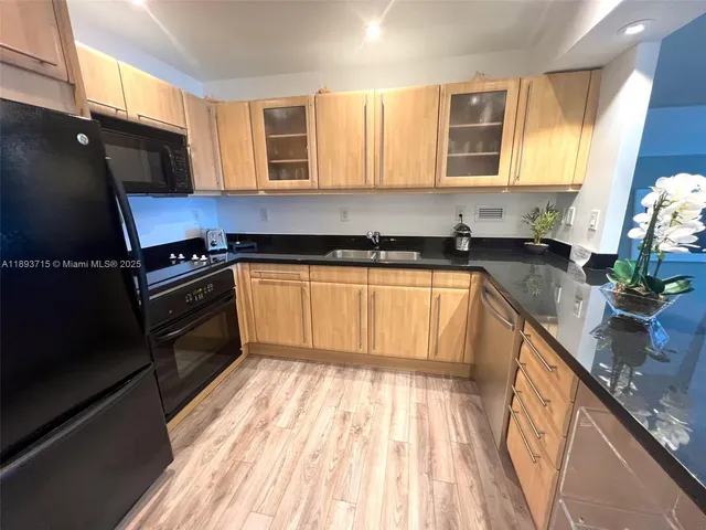 a kitchen with granite countertop a sink a stove top oven a cabinetry and a potted plant