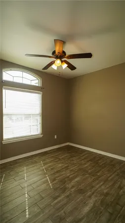 a view of an empty room with window and chandelier fan