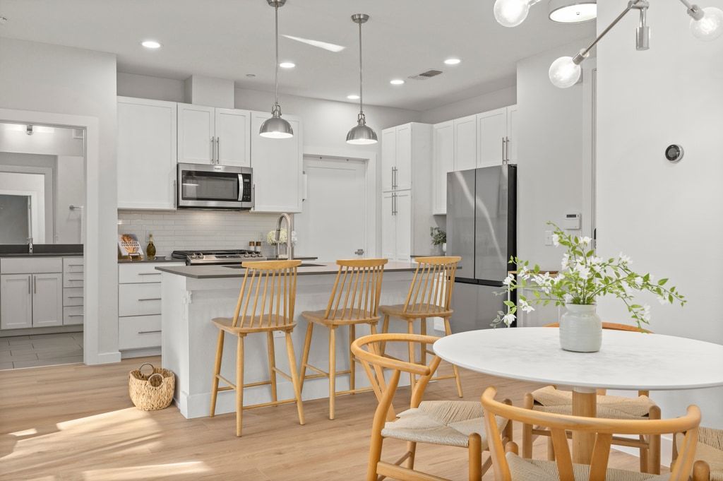 a kitchen with stainless steel appliances kitchen island granite countertop a kitchen island a stove a table and chairs