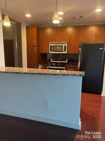 a kitchen with stainless steel appliances granite countertop a sink a stove top oven and a refrigerator