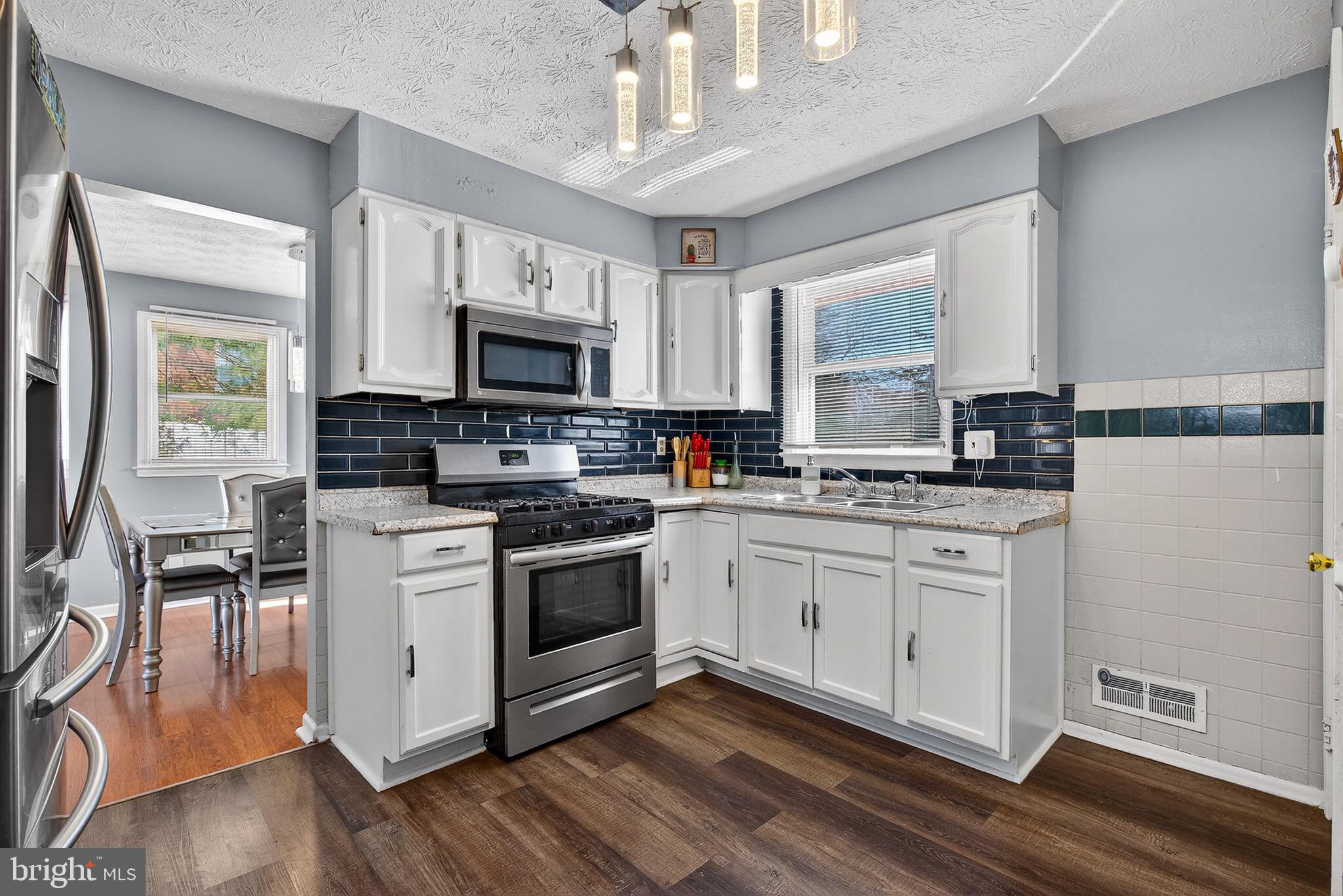 3505 East Joppa Road Parkville, MD 21234 - Photo 6 of 42 a kitchen with granite countertop a stove top oven a sink dishwasher a dining table and chairs with wooden floor