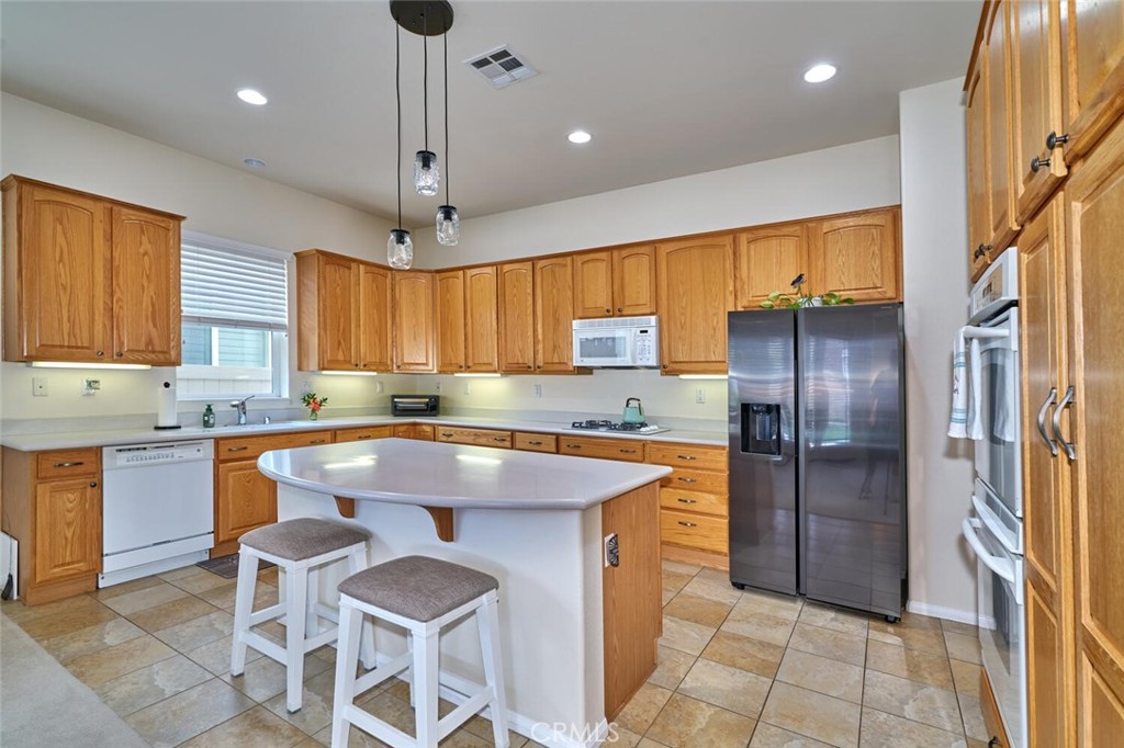 860 Annandale Road Beaumont, CA 92223 - Photo 19 of 61 a large kitchen with a table chairs refrigerator and microwave