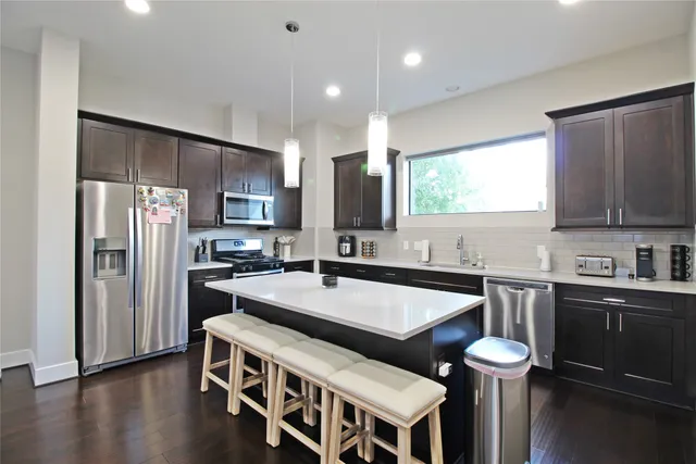 a large kitchen with stainless steel appliances granite countertop a stove a sink a refrigerator and a microwave