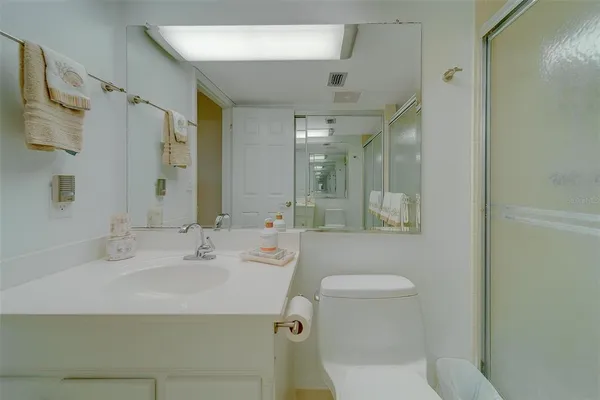 a bathroom with a toilet a sink a mirror a shower and vanity