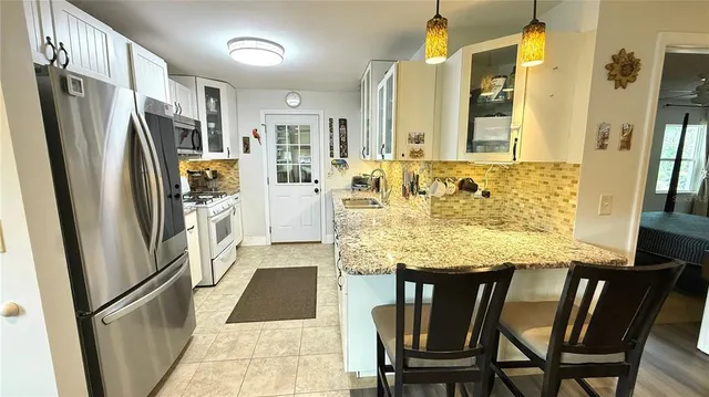 a kitchen with stainless steel appliances granite countertop furniture refrigerator and wooden floor