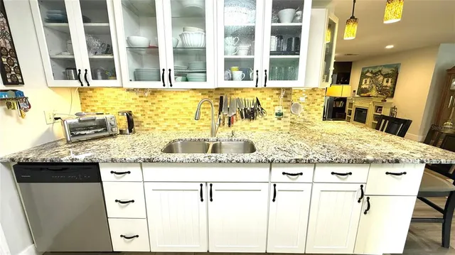 a kitchen with kitchen island granite countertop a sink and a white wooden cabinets