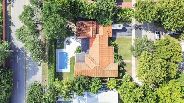 an aerial view of a house with outdoor space and trees all around