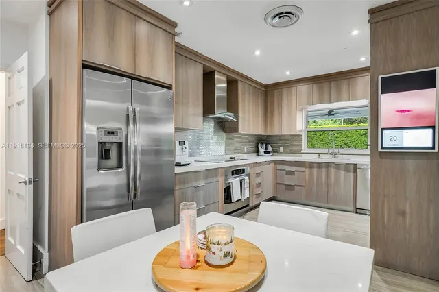 a kitchen with stainless steel appliances granite countertop a refrigerator a sink a stove and white cabinets