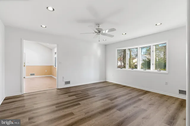 a view of an empty room with a window and wooden floor