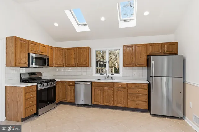 a kitchen with stainless steel appliances granite countertop a refrigerator a stove top oven a sink and dishwasher