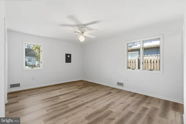 a view of empty room with wooden floor and fan