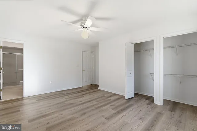 an empty room with wooden floor and fan