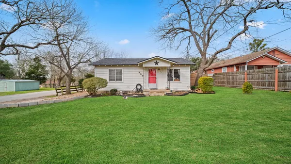 a front view of a house with a garden and trees