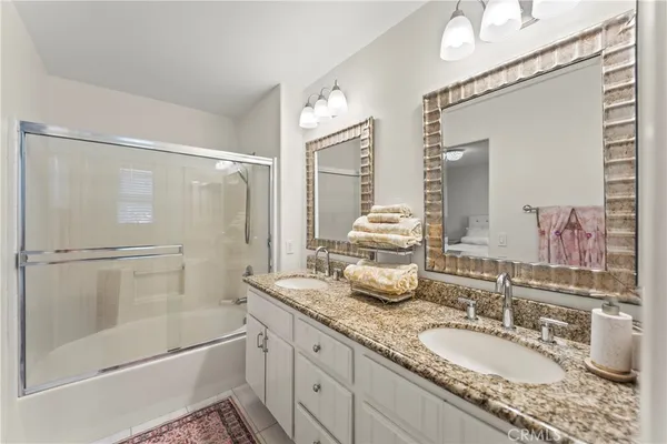 a bathroom with a granite countertop sink mirror and a shower