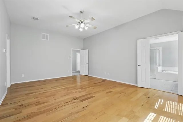 a view of an empty room with chandelier and wooden floor