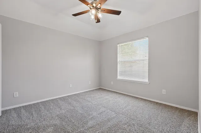 an empty room with a window and a fan