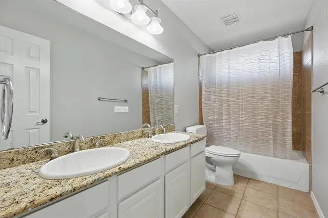 a bathroom with a granite countertop sink a toilet a mirror and shower